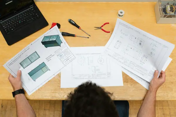 Ingeniero revisando planos técnicos de diseño mecánico sobre una mesa