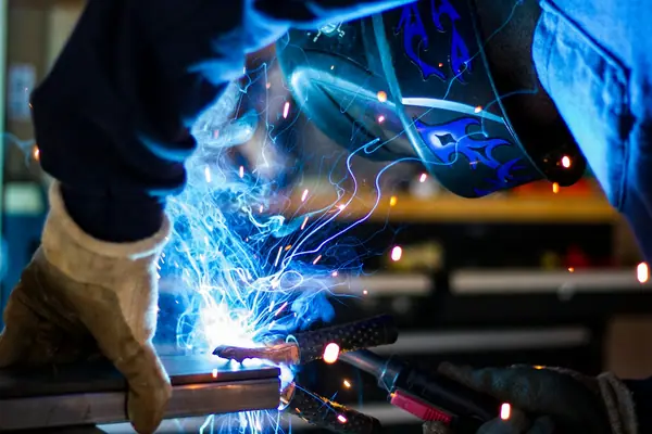 Soldador trabajando con arco eléctrico en un proyecto industrial